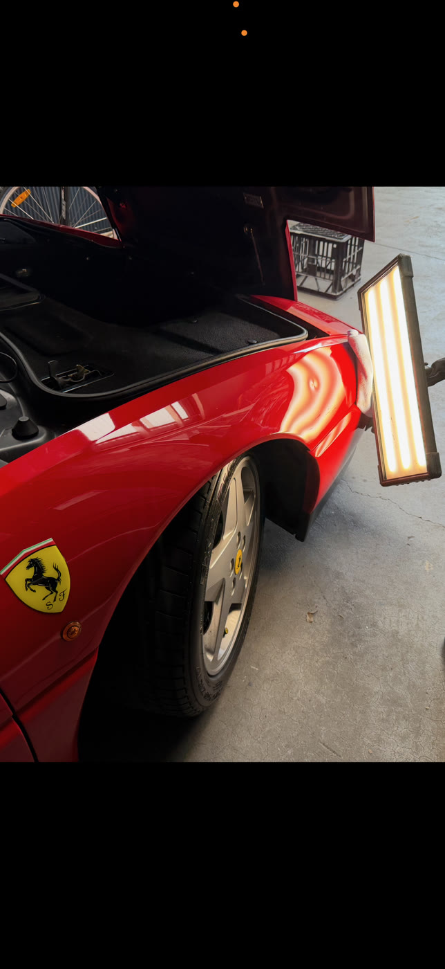 PDR light bar reflecting on a Ferrari panel during paintless dent removal