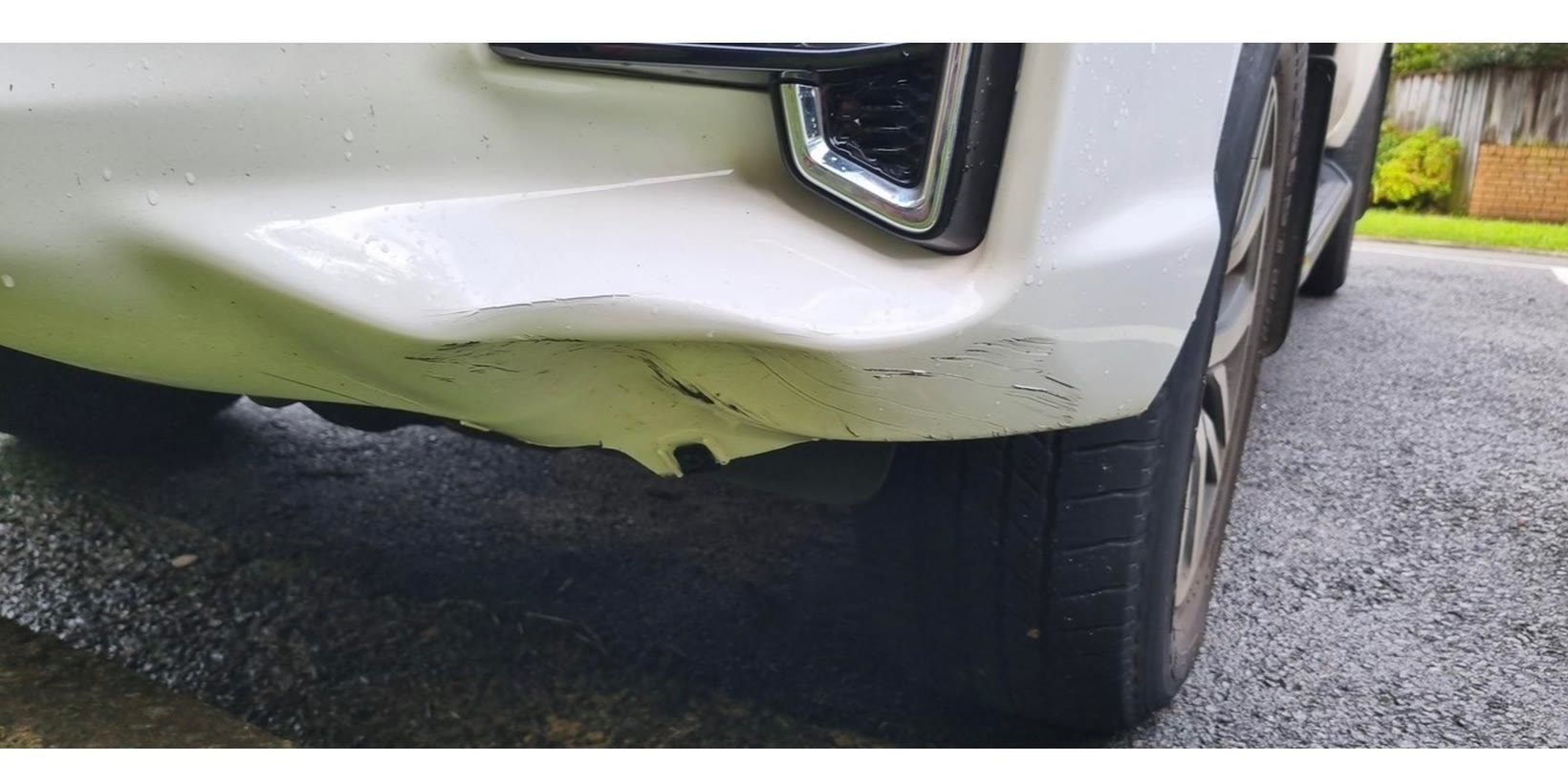 White SUV front bumper torn and scraped after a collision